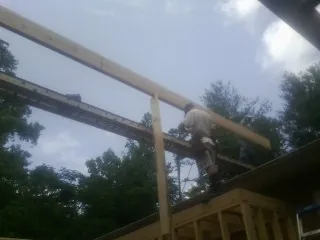 Carpenter setting a ridge beam over a new addition frame — Ice Dam Removal by Roofing Brothers in Hill