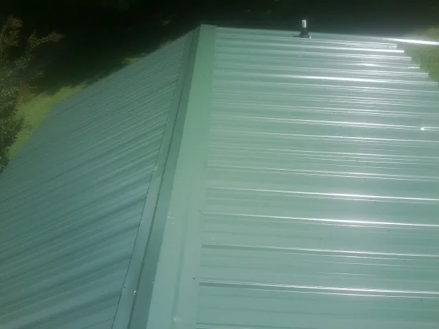 New green metal panels meeting at the ridge of a roof — Flat Roof Repair work by our crew in Hill
