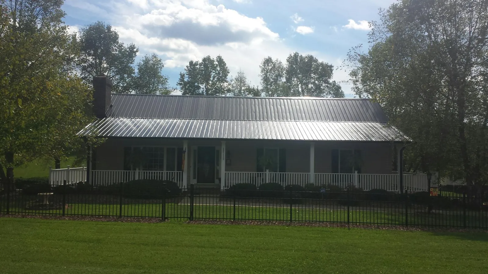 Gray metal roof on a brick ranch with a full width front porch — Gutter Guard Installation work by our crew in Hill